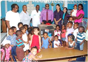 Bank manager Imran Saccoor (centre) stands with from left Reverend Dr Selby Ross, Pastor of the Presbyterian Church and coordinator of the Centre Marianne Tinnie second left. Other bank staff workers of the centre and some of the children share the moment.